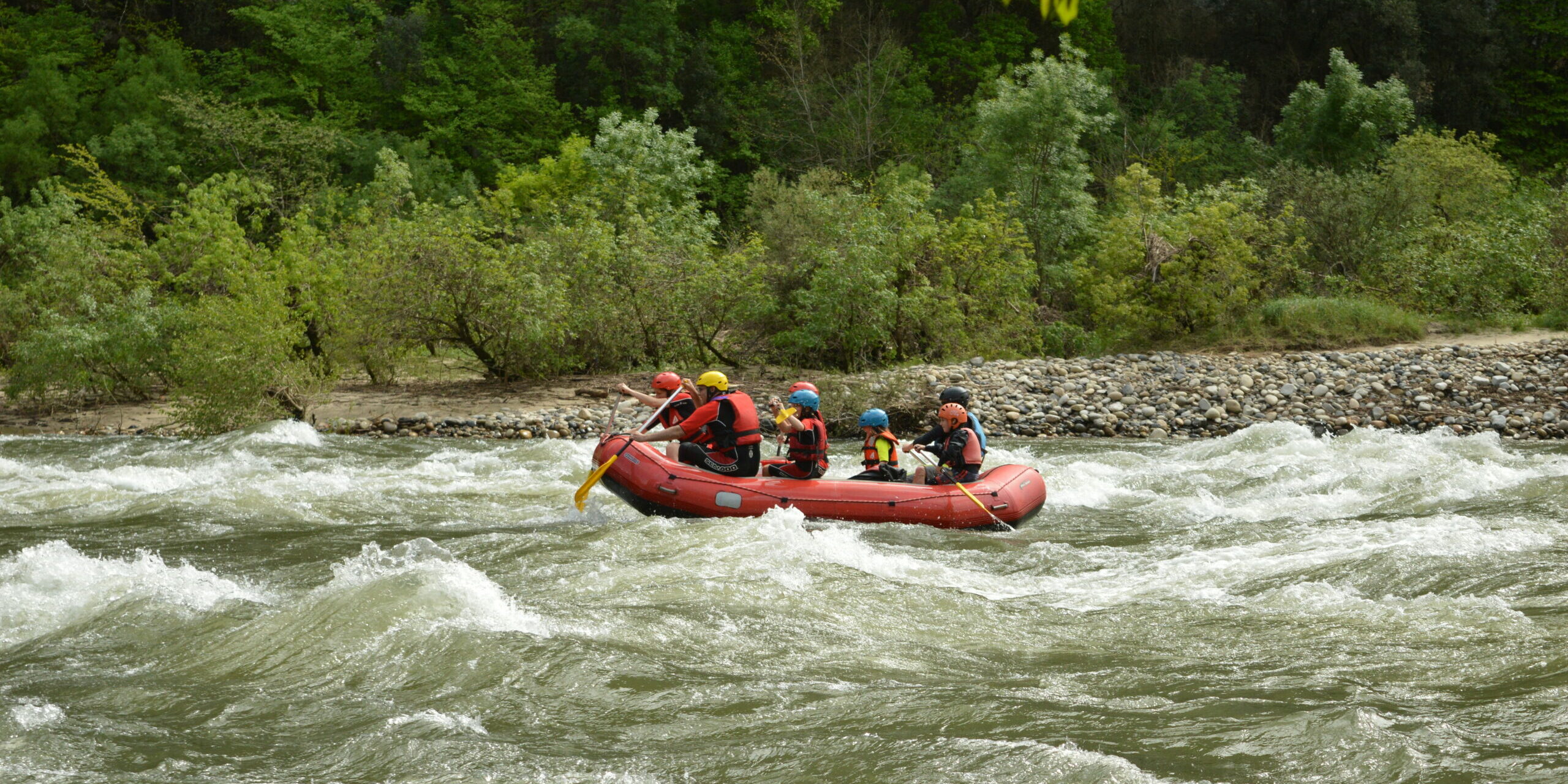 rafting une famille dans un rafting, 2 adultes et 4 enfants un guide, le raft est rouge, ils sont dans des rapides sur la rivière Ardèche