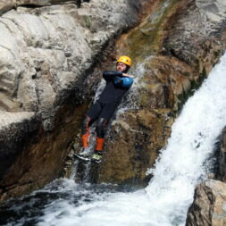 une personne vêtue d'une combinaison néoprène et d'un casque saute dans la rivière