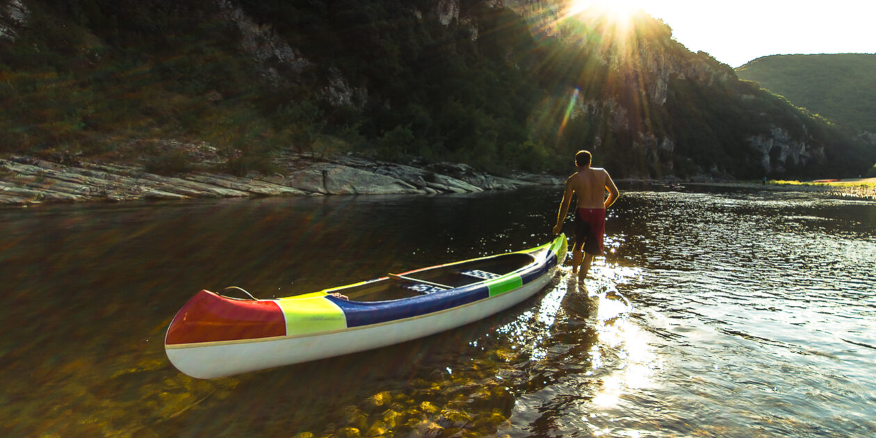 Canoë sur l’Ardèche Un homme tire un canoë sur l'Ardèche