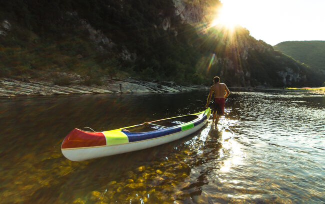 Canoë sur l’Ardèche Un homme tire un canoë sur l'Ardèche