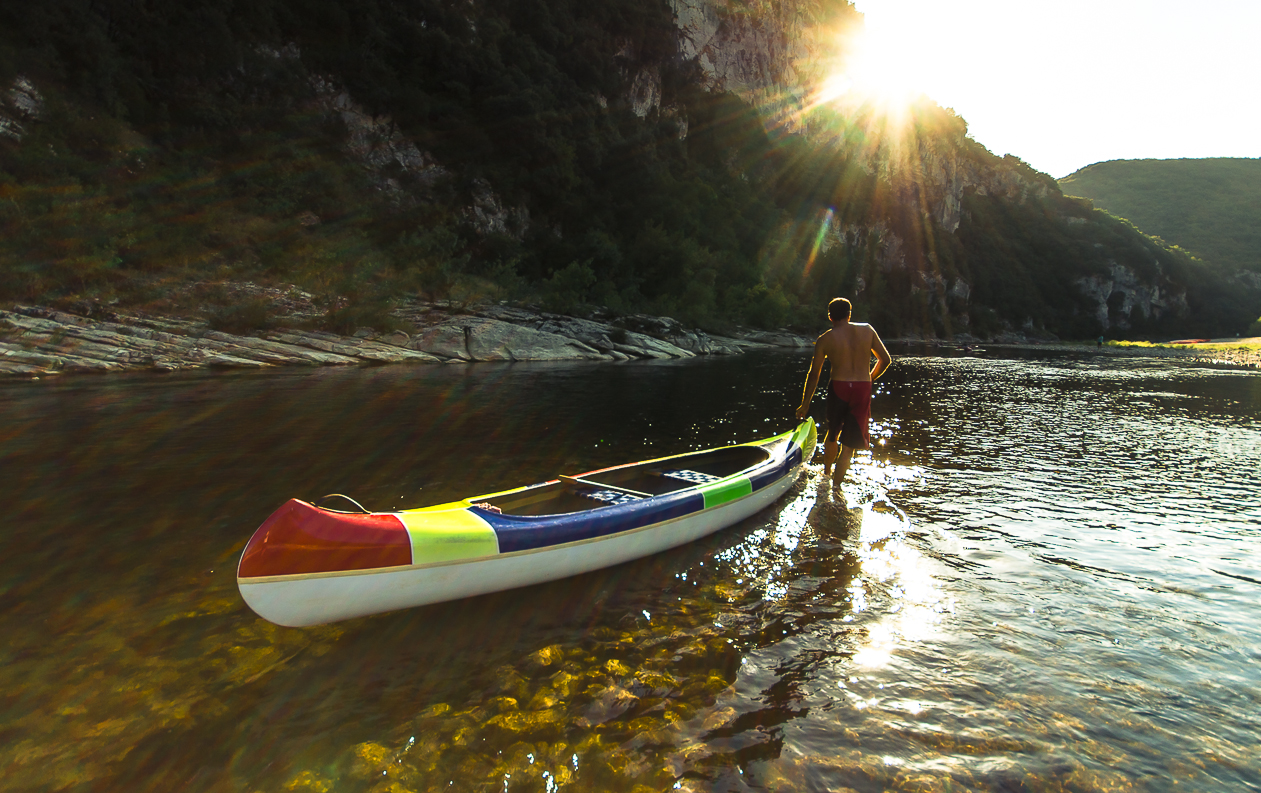 Canoë sur l’Ardèche Un homme tire un canoë sur l'Ardèche