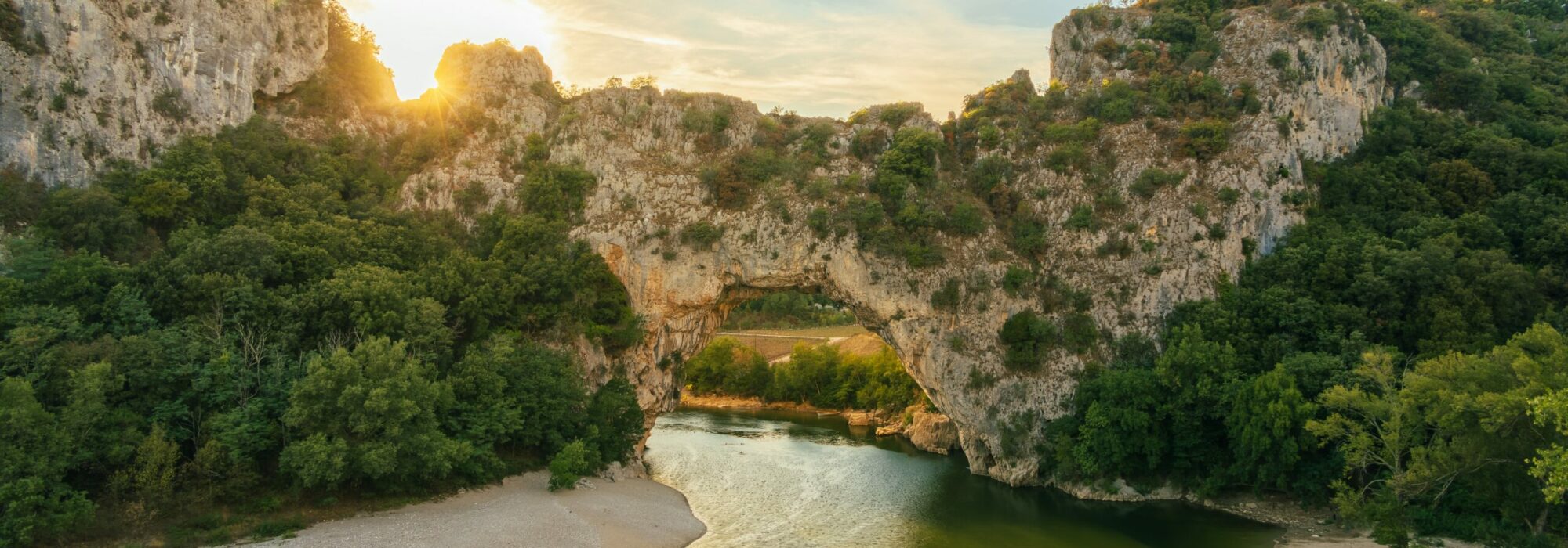 le pont d'arc avec le lever du soleil, le soleil qui éclaire la plage rive gauche, la rivière ardèche à vallon pont d'arc