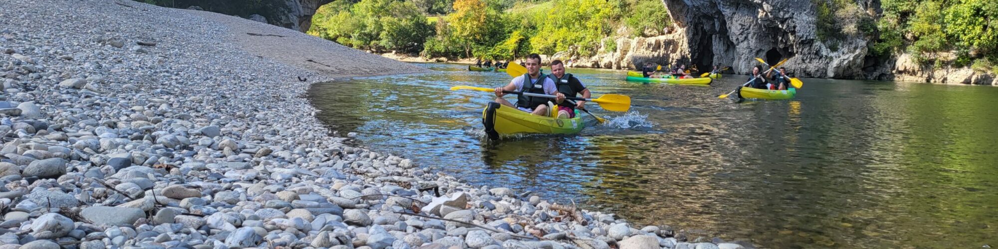 un canoë jaune sous le pont d'arc avec 2 personnes