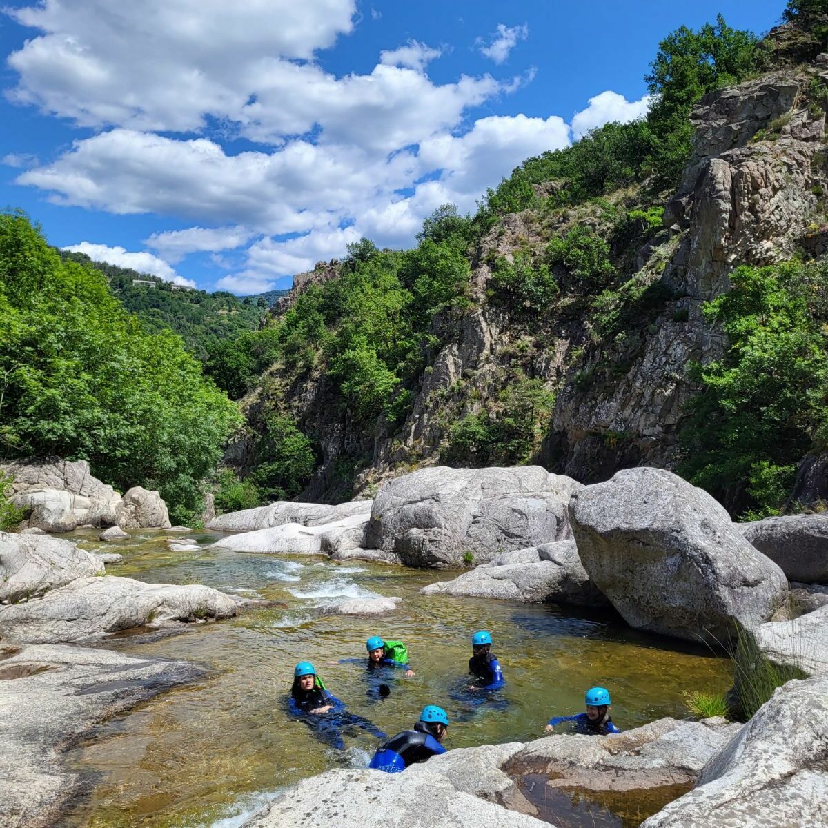 5 personnes sont dans une vasque naturelle équipés de casques et combinaisons néoprène