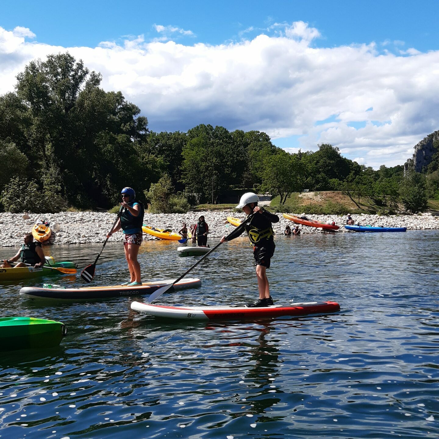 3 personnes sur des paddles avec une pagaie , gilet et casque sur la rivière Ardèche, des hommes en canës
