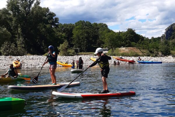 3 personnes sur des paddles avec une pagaie , gilet et casque sur la rivière Ardèche, des hommes en canës sur la rivière