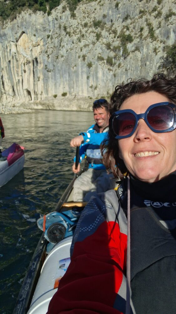 sur la rivière Ardèche, un homme est au gouvernail, une femme est devant avec des lunettes de soleil, ils font du canoë sur l'Ardèche