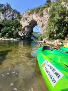 plage du pont d'arc, canoë la petite mer avec derière le pont d'arc, on voit le numéro de téléphone, sur les bateaux jaunes et verts