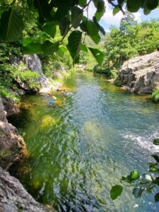 vasque avec une eau vert émeraude, 4 personnes en canyon, combinaisons et casque jaunes